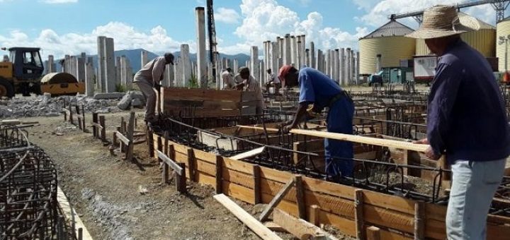 En imagen trabajadores en la construcción de la planta de piensos de Santiago de Cuba