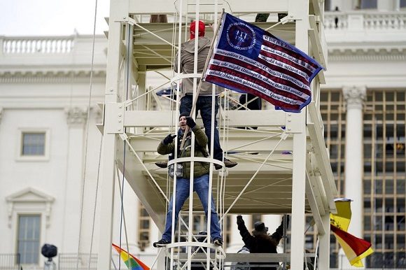 Partidarios de Trump escalaron estructuras metálicas frente al Capitolio este miércoles. foto: Julio Cortez / AP